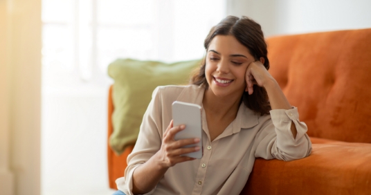 smiling-young-woman-with-smartphone-relaxing-floor-home